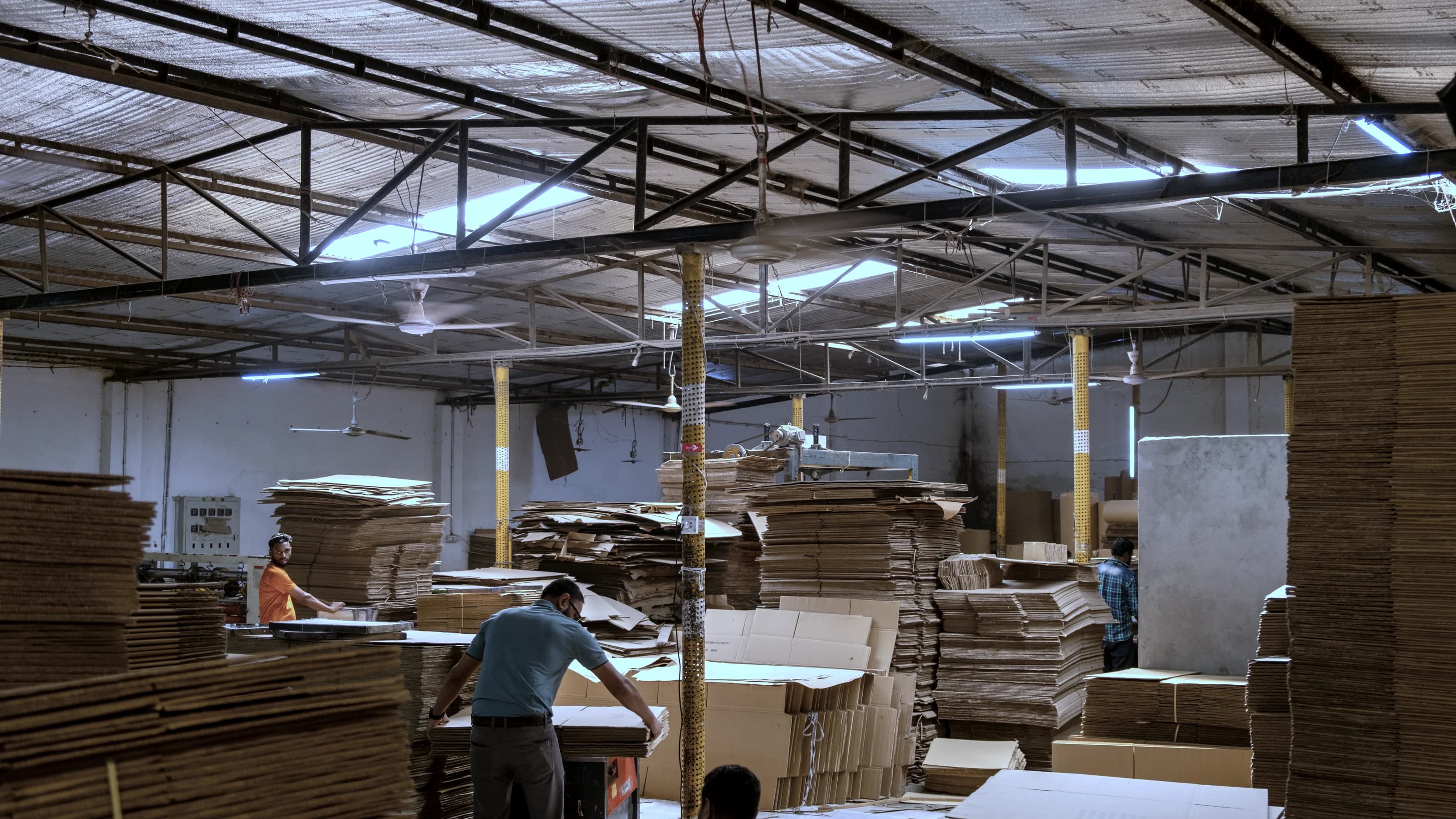 Corrugation floor at the Ashulia facility, stacks of cut board and the team working