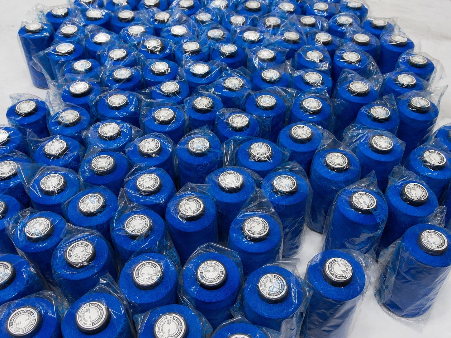A mass of blue sewing thread cones packed in poly bags, seen from above