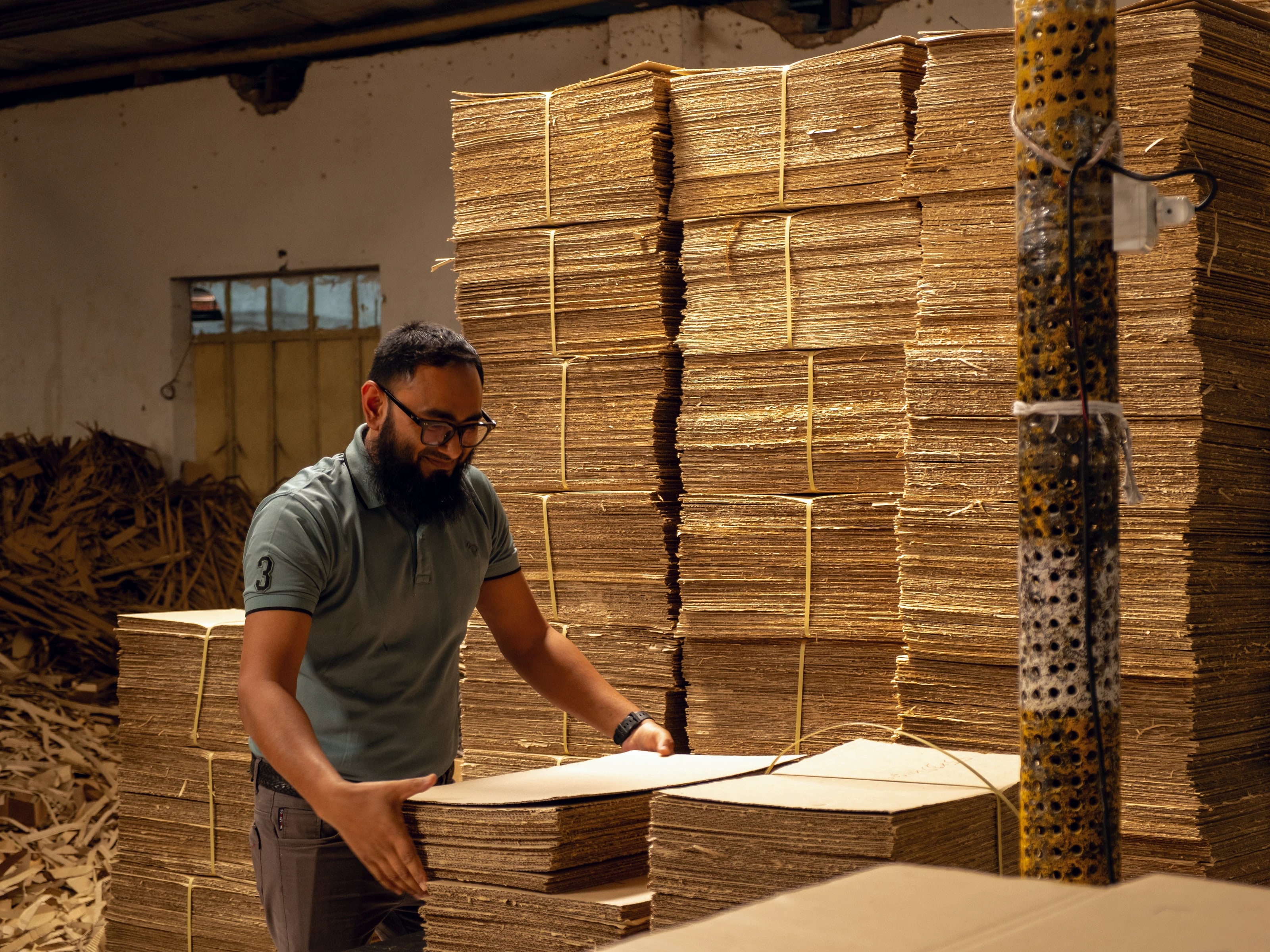 A team member stacking corrugated board on the corrugation floor in warm directional light