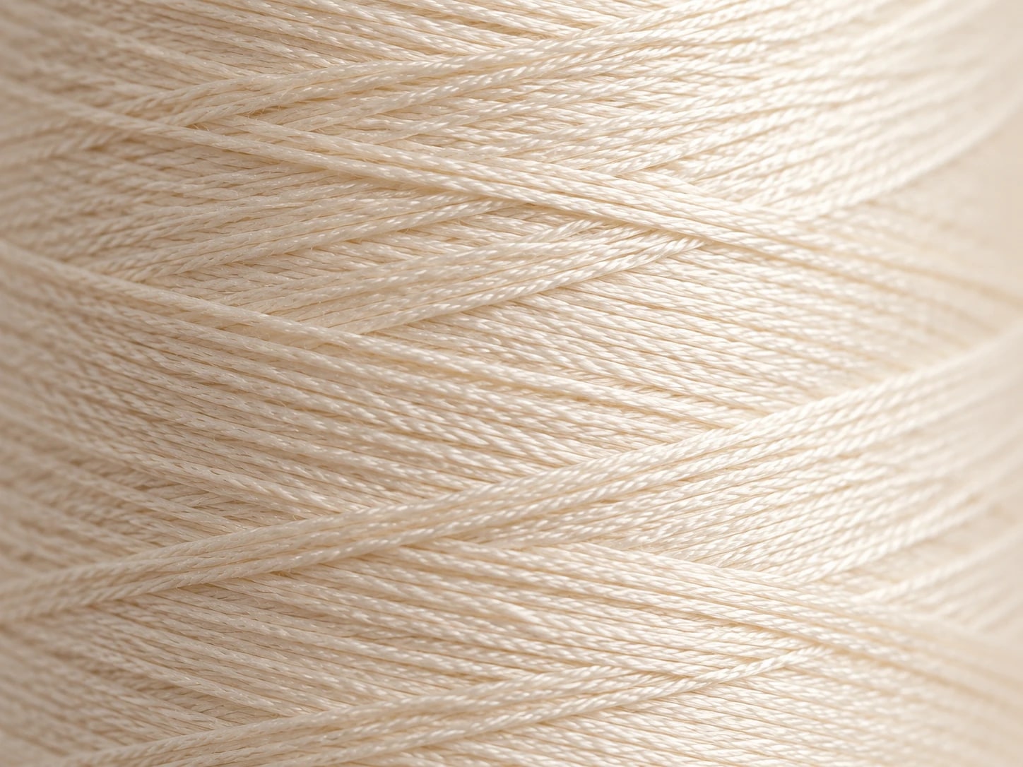 Close view of cream sewing thread wound in crossing layers
